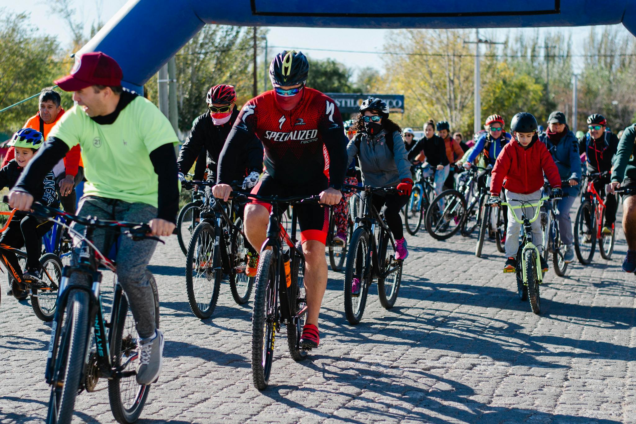 Dynamic group bicycle race in urban area, showcasing diverse cyclists enjoying a sunny day.