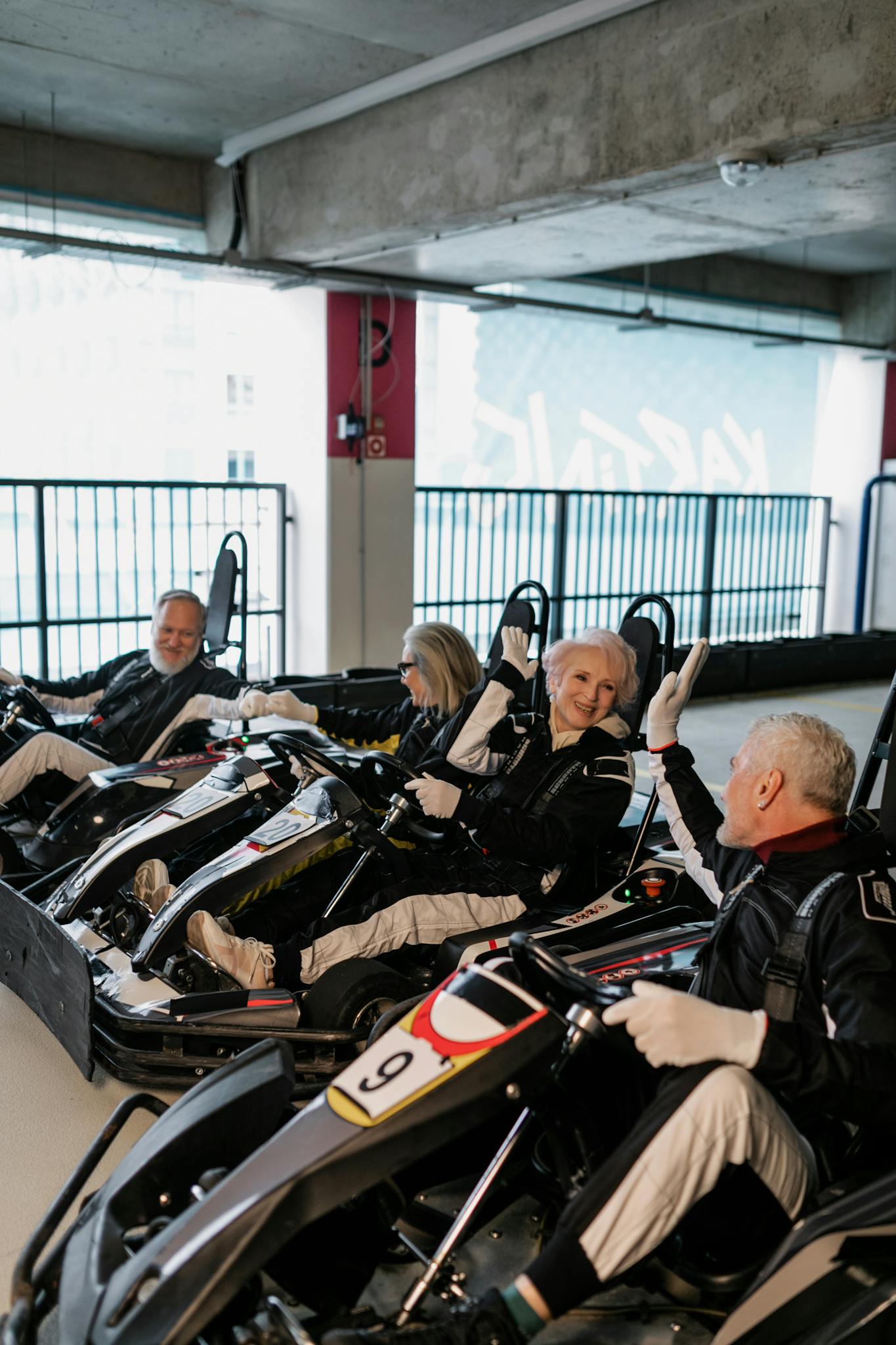 Senior adults having fun racing go-karts indoors, showcasing joy and friendship.